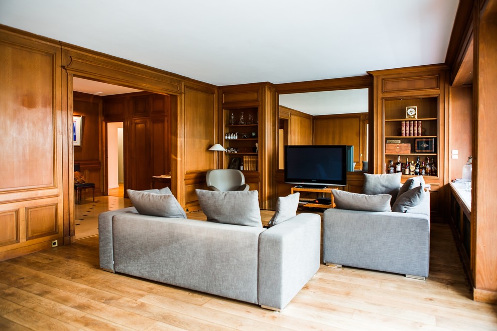 Modelo de sala de estar con biblioteca abierta tradicional renovada de tamaño medio sin chimenea con paredes marrones, suelo de madera en tonos medios y televisor independiente