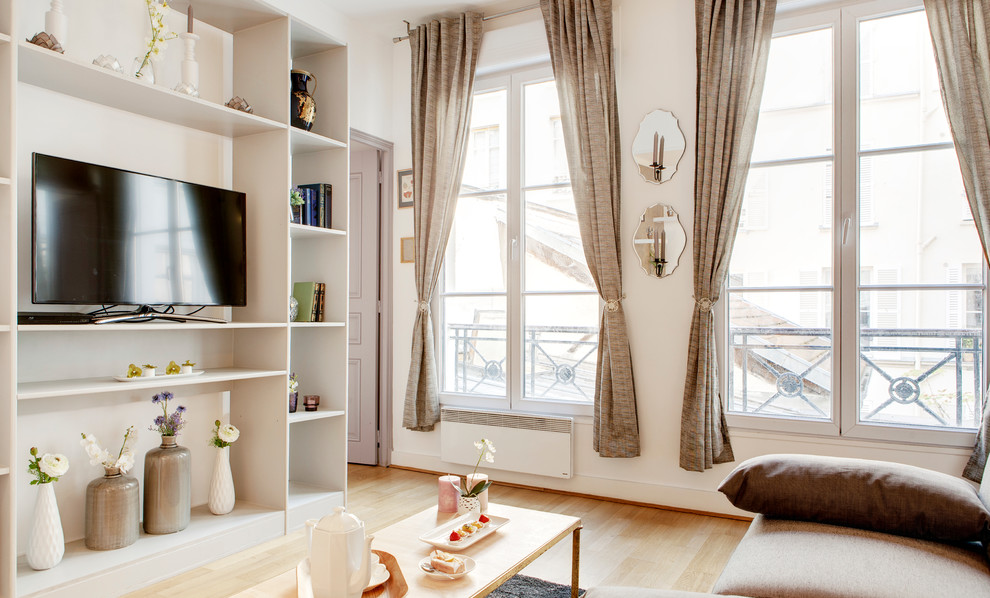 На фото: изолированная гостиная комната среднего размера в современном стиле с белыми стенами, светлым паркетным полом, отдельно стоящим телевизором и коричневым диваном