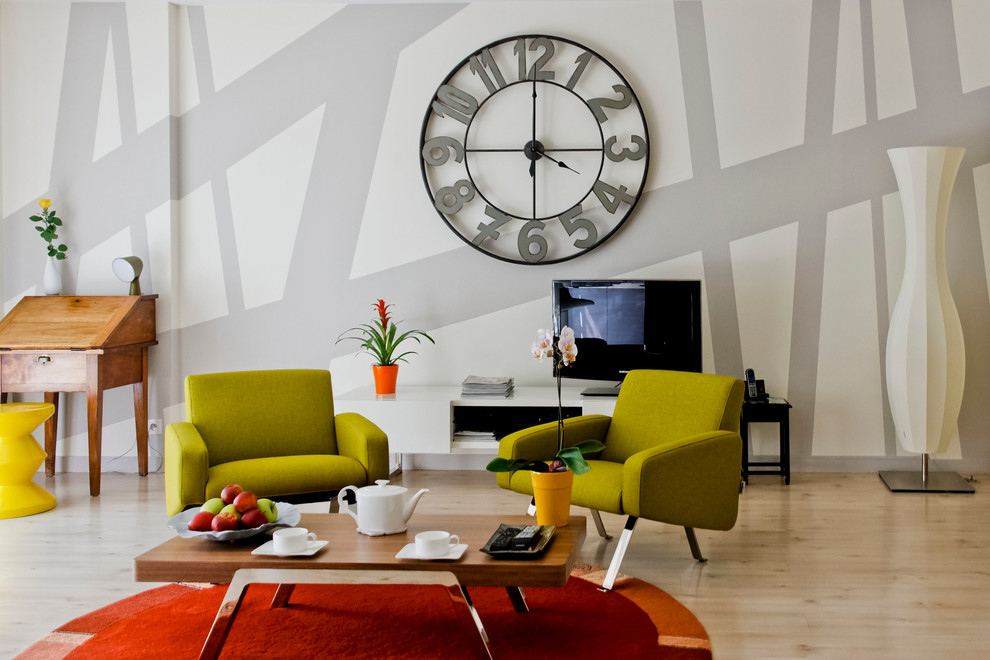 Foto de salón abierto bohemio de tamaño medio sin chimenea con paredes multicolor, suelo de madera clara, televisor independiente y alfombra