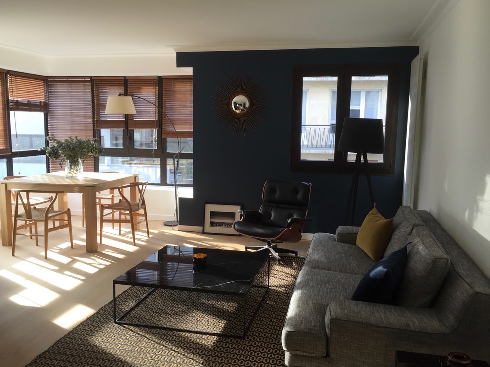 Diseño de sala de estar abierta contemporánea grande con paredes azules, suelo de madera clara y televisor colgado en la pared
