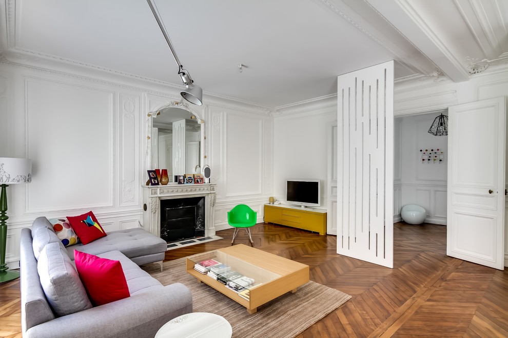 Geräumiges, Offenes Modernes Wohnzimmer mit weißer Wandfarbe, braunem Holzboden, Kamin, Kaminumrandung aus Stein und freistehendem TV in Paris