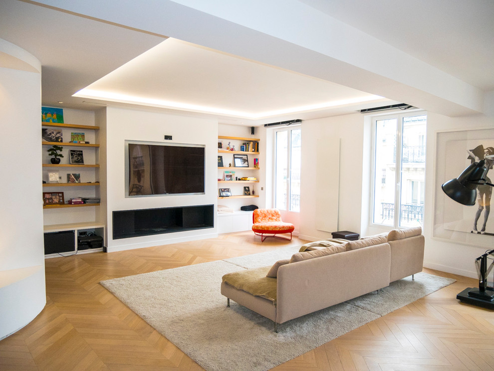 Réalisation d'une grande salle de séjour design ouverte avec un bar de salon, un mur blanc, parquet clair, un téléviseur encastré et un sol marron.