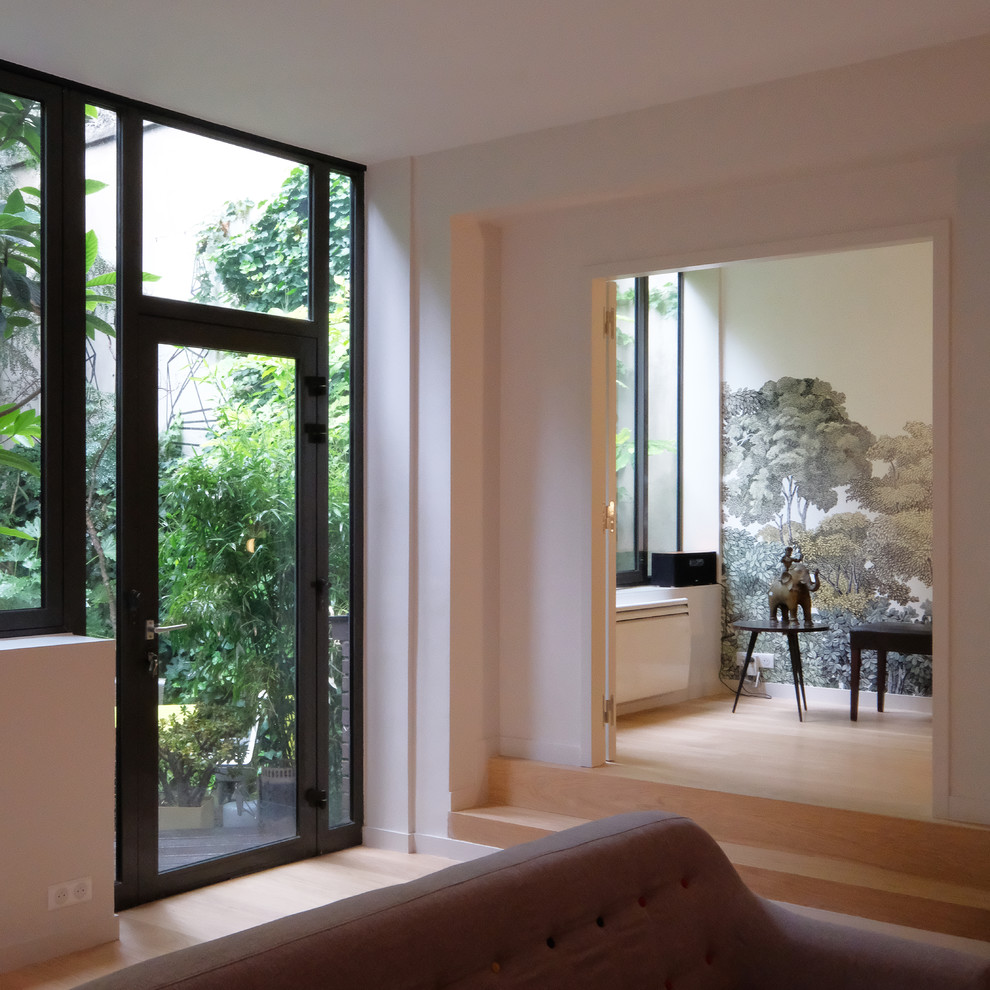 Immagine di un grande soggiorno design aperto con pareti bianche, parquet chiaro e pavimento beige