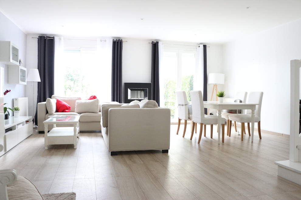 Mittelgroßes Nordisches Wohnzimmer mit weißer Wandfarbe, hellem Holzboden, Hängekamin, Kaminumrandung aus Metall und beigem Boden in Paris