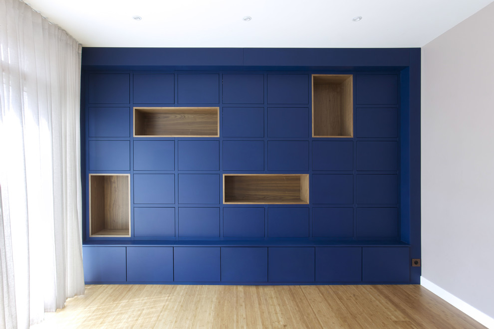 Стильный дизайн: огромная изолированная гостиная комната в современном стиле с с книжными шкафами и полками, синими стенами, полом из бамбука и коричневым полом без камина, телевизора - последний тренд