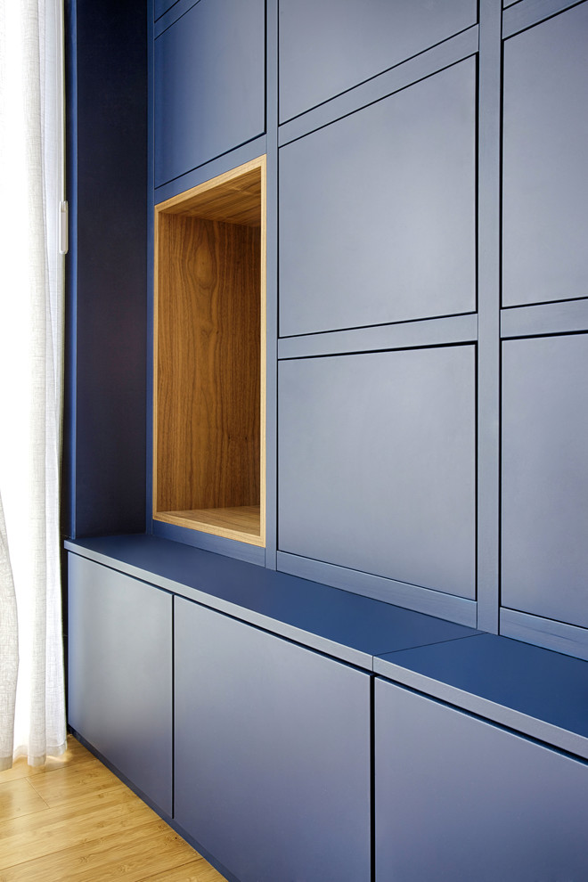 Идея дизайна: огромная изолированная гостиная комната в современном стиле с с книжными шкафами и полками, синими стенами, полом из бамбука и коричневым полом без камина, телевизора