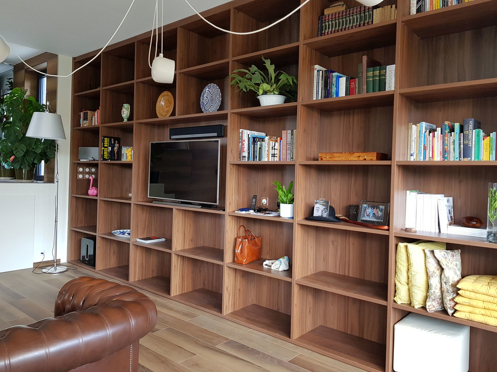 Immagine di un grande soggiorno tropicale aperto con libreria, parquet chiaro, camino sospeso e TV autoportante
