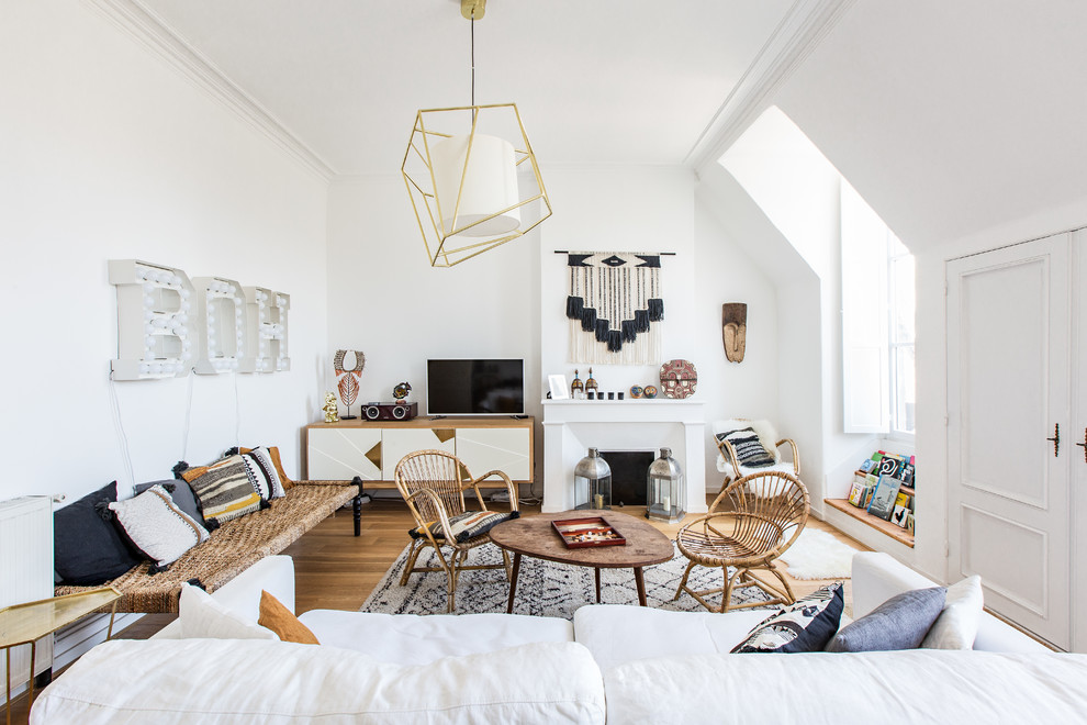 На фото: гостиная комната в скандинавском стиле с белыми стенами, светлым паркетным полом, стандартным камином и отдельно стоящим телевизором с