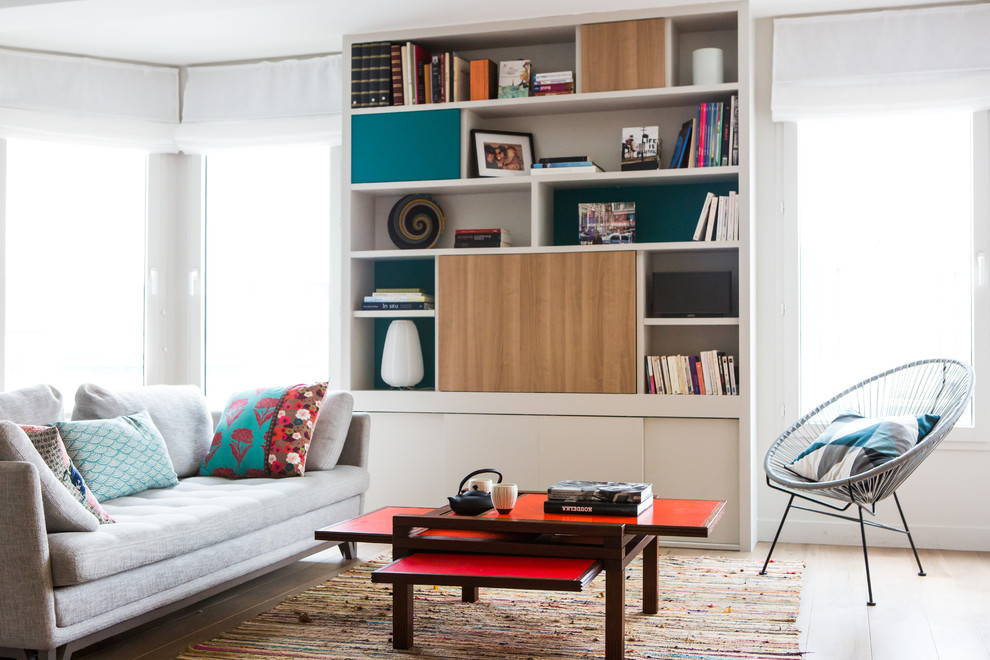 Bild på ett funkis allrum med öppen planlösning, med ljust trägolv, en dold TV, vita väggar och beiget golv