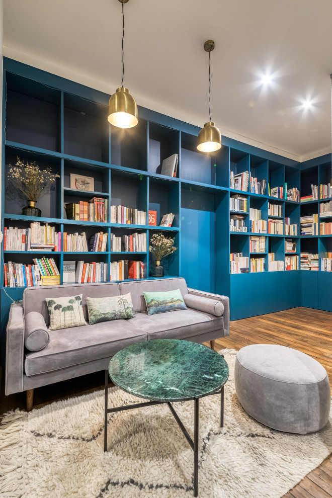 Cette photo montre un bureau tendance de taille moyenne avec une bibliothèque ou un coin lecture, un mur bleu, un sol en bois brun, aucune cheminée, un sol marron et un bureau indépendant.