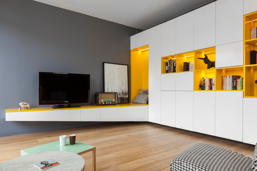 Cette image montre une salle de séjour design de taille moyenne et ouverte avec un mur gris, parquet clair, aucune cheminée, un téléviseur indépendant et un sol marron.