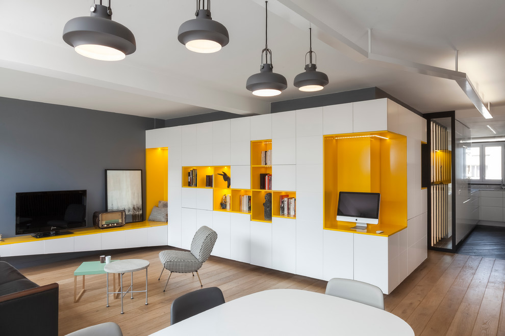 Offenes, Mittelgroßes Modernes Wohnzimmer ohne Kamin mit grauer Wandfarbe, hellem Holzboden, freistehendem TV und braunem Boden in Paris