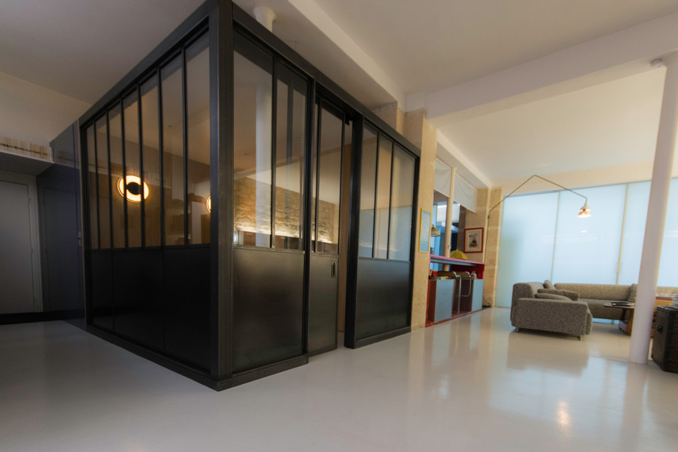 Imagen de sala de estar abierta industrial pequeña con paredes blancas, suelo de cemento y suelo gris