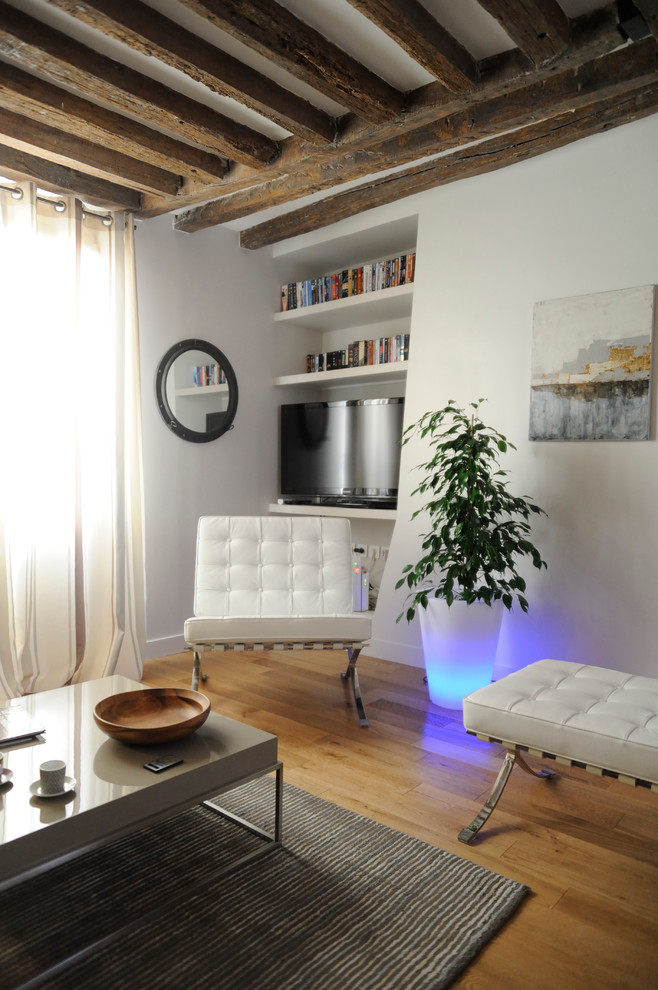 Modelo de sala de estar abierta contemporánea de tamaño medio con paredes blancas, suelo de madera en tonos medios y televisor independiente