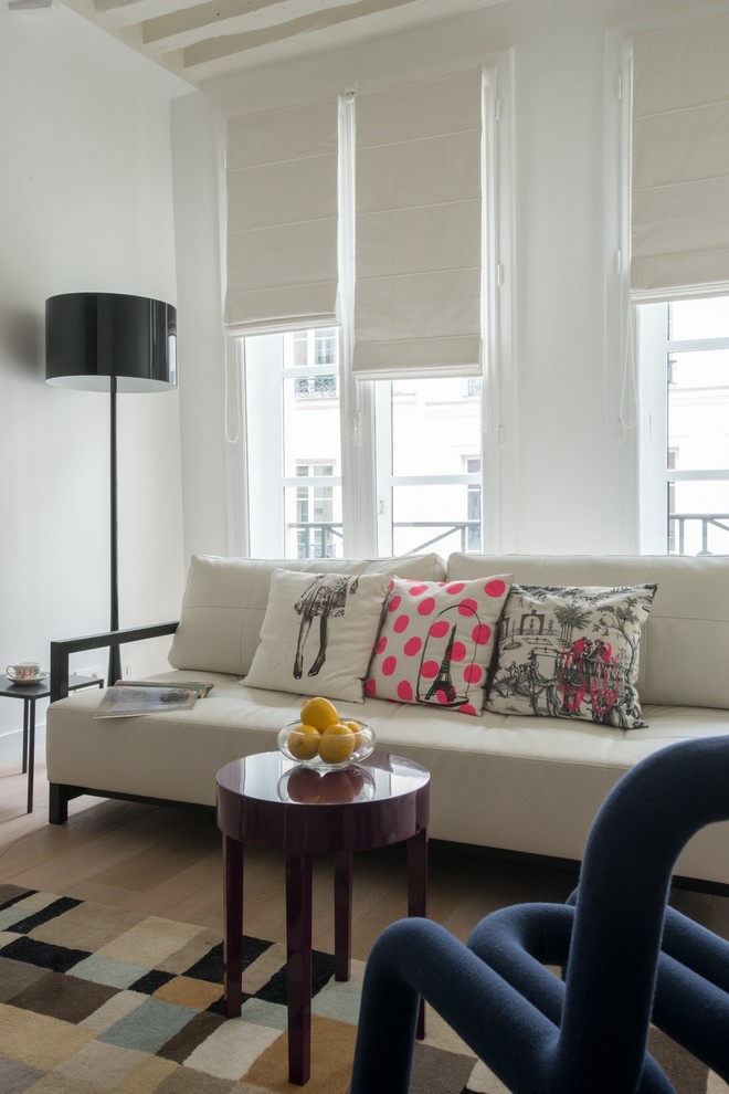 Modelo de sala de estar abierta actual de tamaño medio sin televisor con paredes blancas, suelo de madera clara y vigas vistas