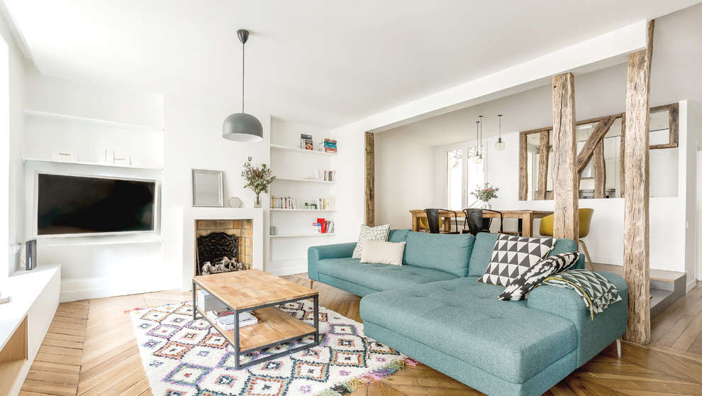 Offenes, Großes Skandinavisches Wohnzimmer mit weißer Wandfarbe, Kamin, braunem Holzboden, verputzter Kaminumrandung, Multimediawand und braunem Boden in Paris