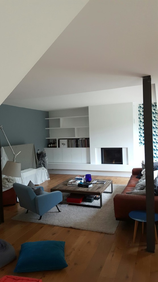 Ejemplo de sala de estar actual con paredes blancas, suelo de madera clara, todas las chimeneas, marco de chimenea de yeso y suelo marrón