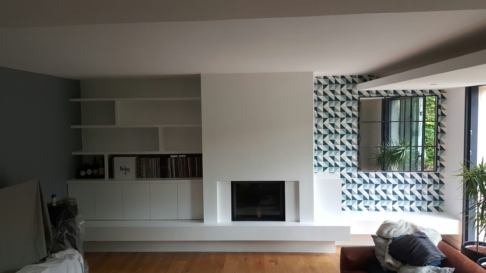 Idées déco pour une salle de séjour contemporaine avec une cheminée standard, un manteau de cheminée en plâtre, un mur blanc et parquet clair.