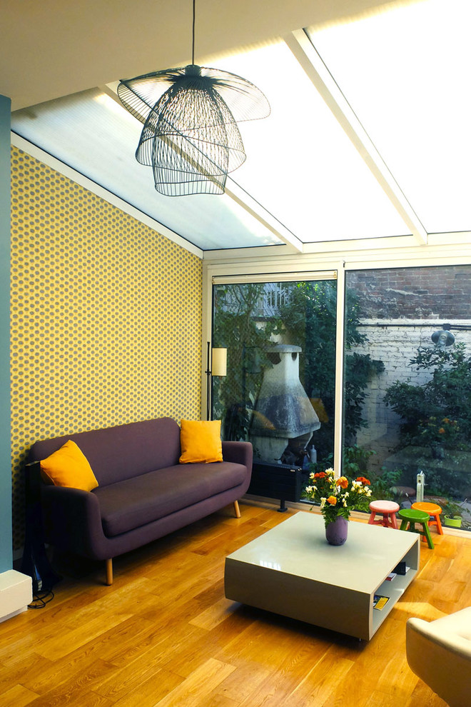 Großes, Fernseherloses, Offenes Retro Wohnzimmer mit gelber Wandfarbe und braunem Holzboden in Paris