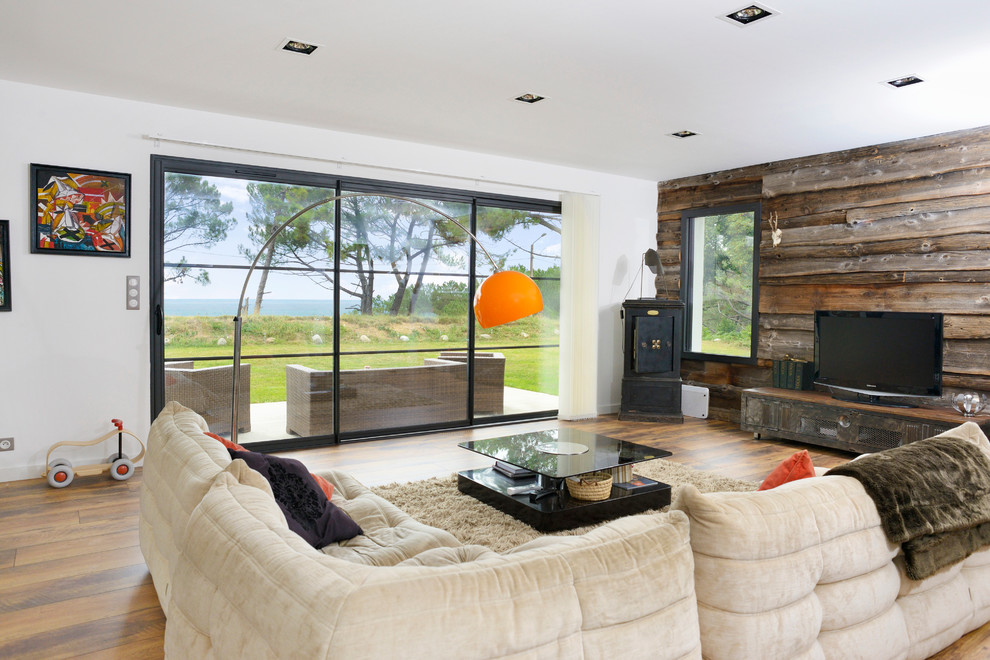 Modernes Wohnzimmer mit weißer Wandfarbe, braunem Holzboden und freistehendem TV in Bordeaux