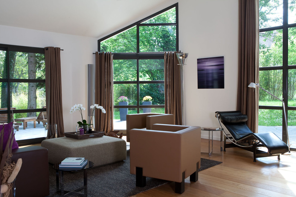 На фото: большая открытая гостиная комната в современном стиле с белыми стенами и светлым паркетным полом без телевизора