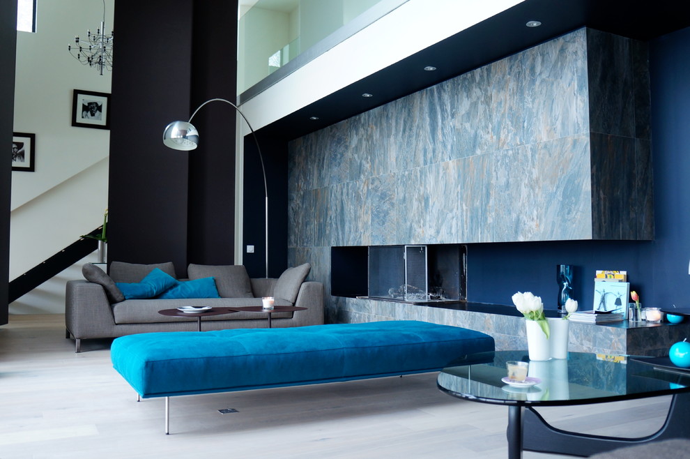 Imagen de sala de estar abierta contemporánea de tamaño medio sin televisor con suelo de madera clara, chimenea lineal, marco de chimenea de piedra y paredes multicolor