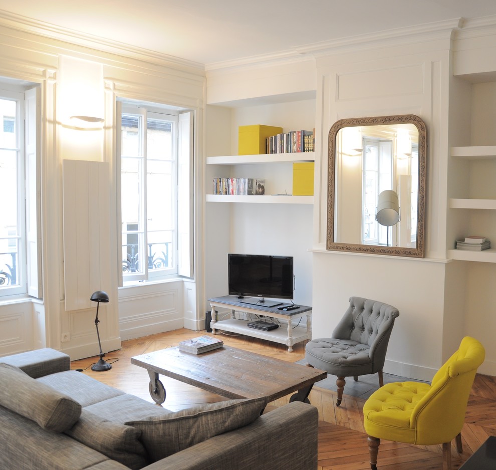 Moderne Bibliothek mit weißer Wandfarbe, braunem Holzboden und freistehendem TV in Lyon