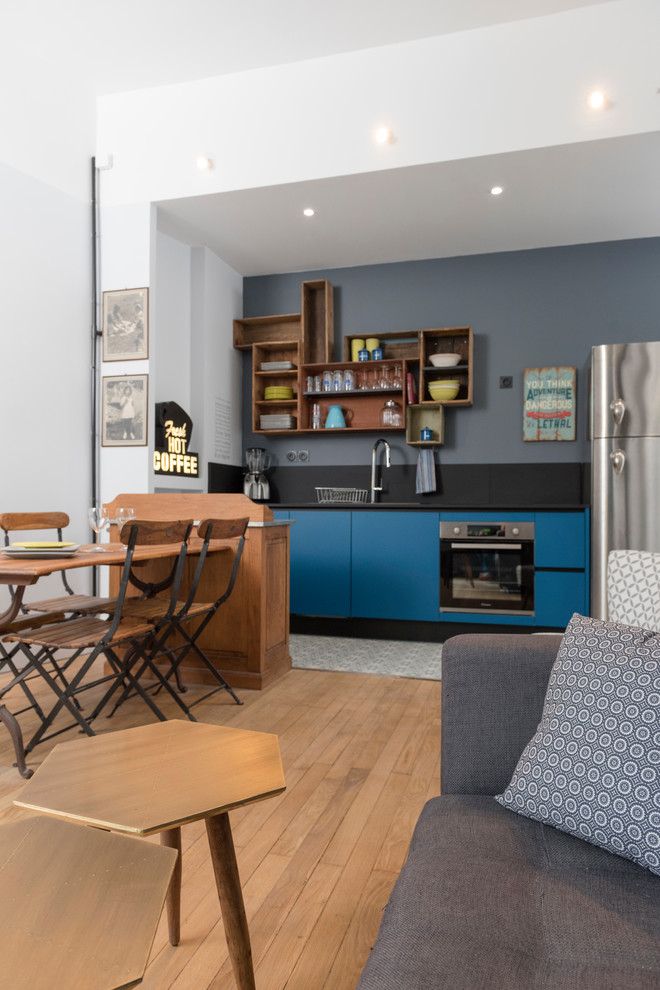 Modelo de sala de estar abierta vintage de tamaño medio con paredes azules y suelo de madera clara