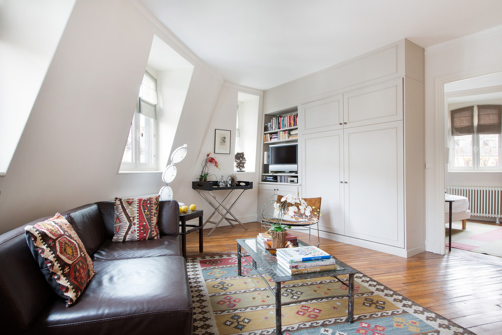Mittelgroße Stilmix Bibliothek ohne Kamin, im Loft-Stil mit weißer Wandfarbe, braunem Holzboden und freistehendem TV in Paris