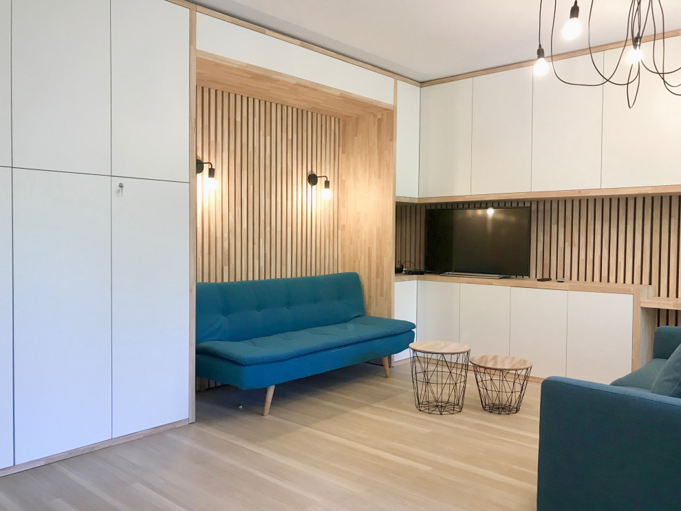 Пример оригинального дизайна: открытая гостиная комната среднего размера в современном стиле с белыми стенами, светлым паркетным полом, отдельно стоящим телевизором и деревянными стенами