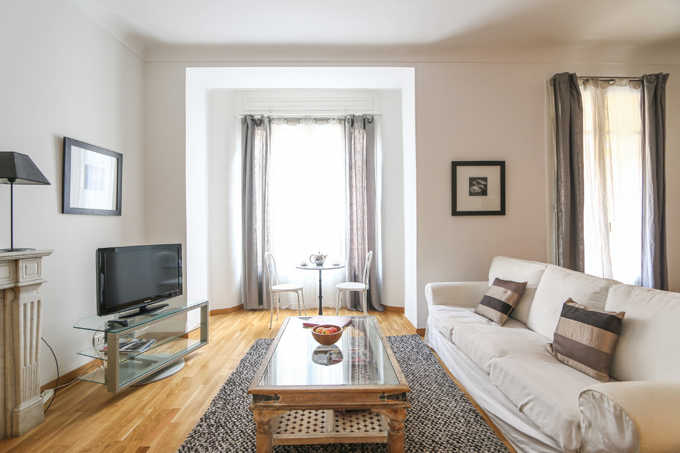 Großes, Offenes Mediterranes Wohnzimmer mit weißer Wandfarbe, braunem Holzboden, Kamin, Kaminumrandung aus Stein und freistehendem TV in Nizza