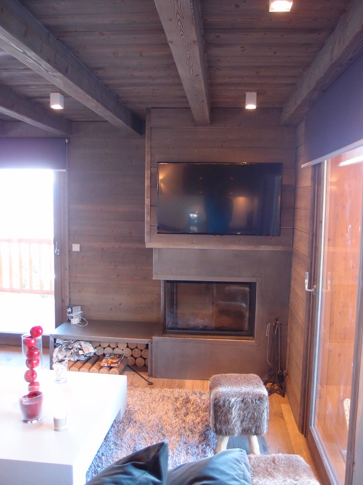 Mittelgroßes Uriges Wohnzimmer mit beiger Wandfarbe, dunklem Holzboden, Eckkamin, Kaminumrandung aus Holz und TV-Wand in Grenoble