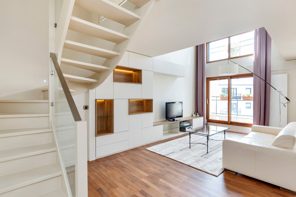 Réalisation d'une grande salle de séjour design ouverte avec un mur blanc, un sol en bois brun et un téléviseur indépendant.