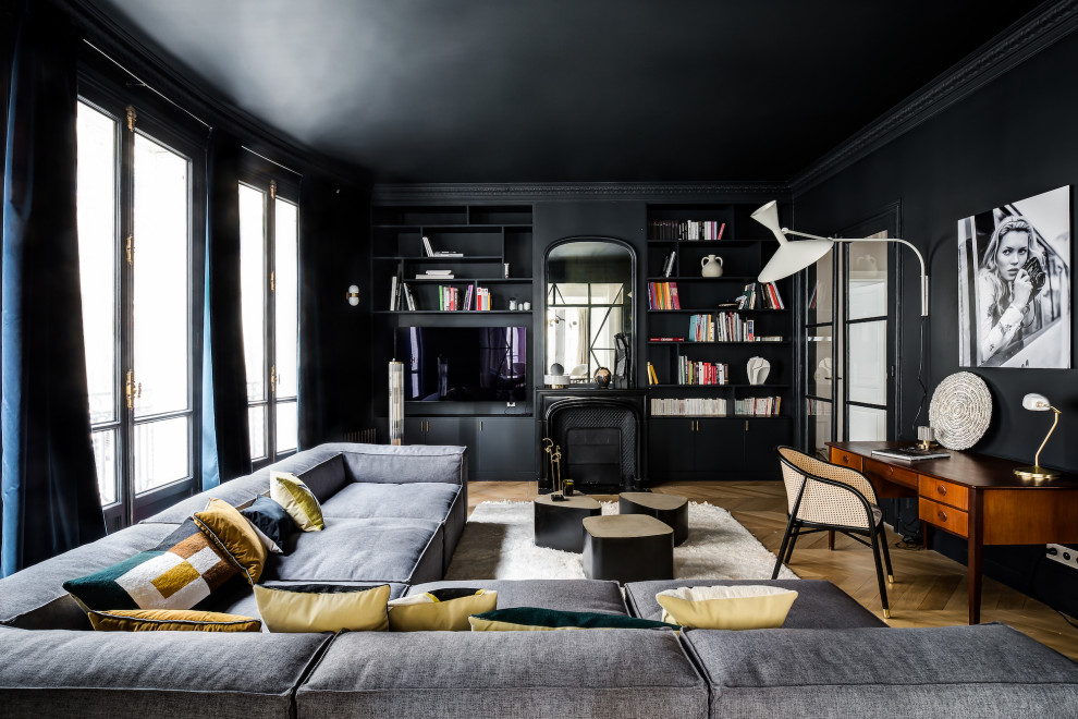 Modelo de sala de estar cerrada y negra actual con paredes negras, suelo de madera en tonos medios, todas las chimeneas, pared multimedia y suelo marrón