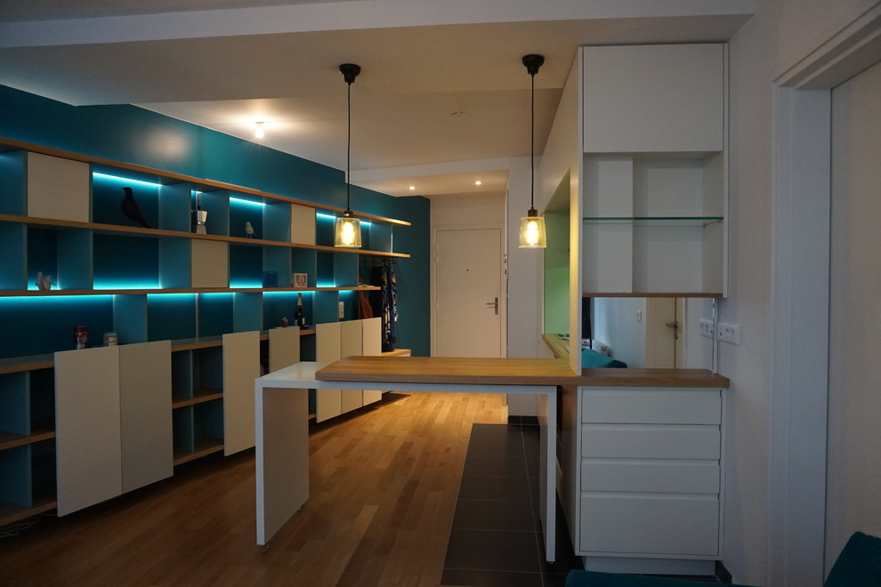 Großes, Offenes Modernes Wohnzimmer mit blauer Wandfarbe, hellem Holzboden, freistehendem TV und braunem Boden in Paris
