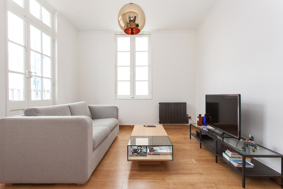 Inspiration pour une salle de séjour minimaliste de taille moyenne et fermée avec un mur blanc, un sol en bois brun et un téléviseur indépendant.