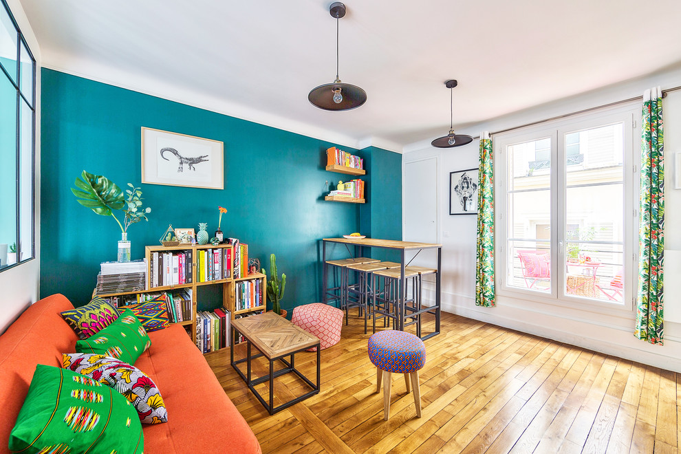 Imagen de sala de estar con barra de bar abierta urbana de tamaño medio con paredes azules, suelo de madera clara, suelo beige y televisor colgado en la pared