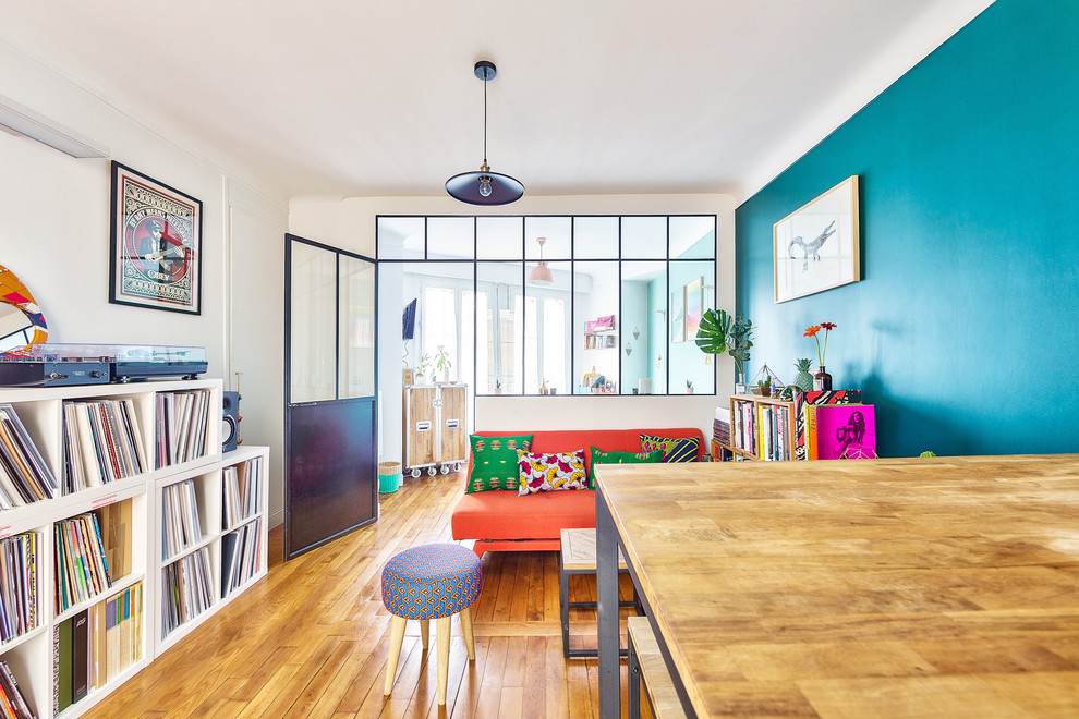 Foto de sala de estar con rincón musical abierta bohemia de tamaño medio sin chimenea con paredes azules, suelo de madera clara, suelo beige y televisor colgado en la pared