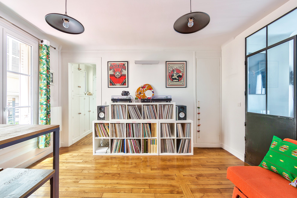 Modelo de sala de estar con rincón musical abierta minimalista de tamaño medio sin chimenea con paredes azules, suelo de madera en tonos medios, televisor colgado en la pared y suelo marrón