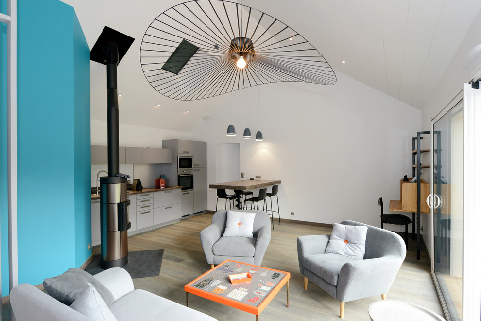 Foto de sala de estar abierta actual de tamaño medio sin televisor con paredes blancas, suelo de madera clara, estufa de leña y marco de chimenea de metal