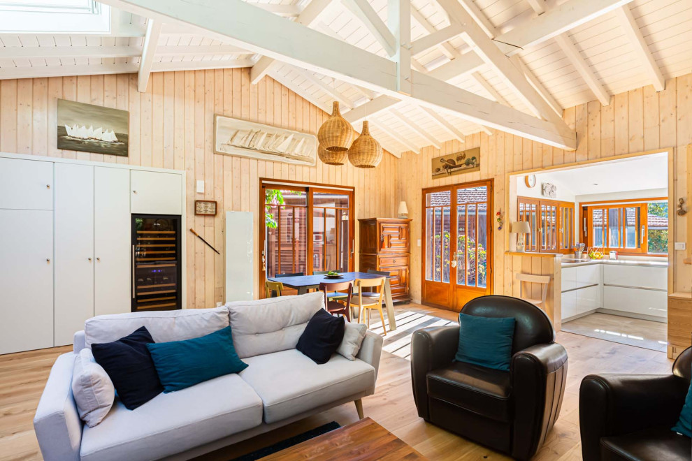 Idées déco pour une salle de séjour bord de mer en bois ouverte avec un mur beige, parquet clair, un sol beige, poutres apparentes, un plafond en lambris de bois et un plafond voûté.