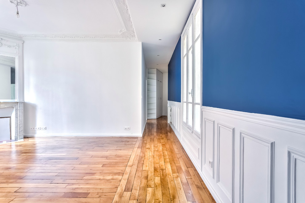Пример оригинального дизайна: большая открытая гостиная комната в классическом стиле с синими стенами, паркетным полом среднего тона, угловым камином, фасадом камина из камня и коричневым полом