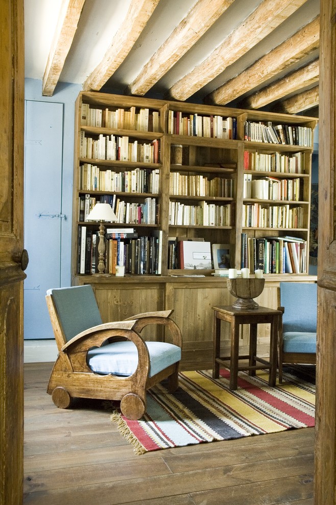 Foto de sala de estar con biblioteca cerrada rural de tamaño medio sin chimenea y televisor con paredes azules y suelo de madera en tonos medios
