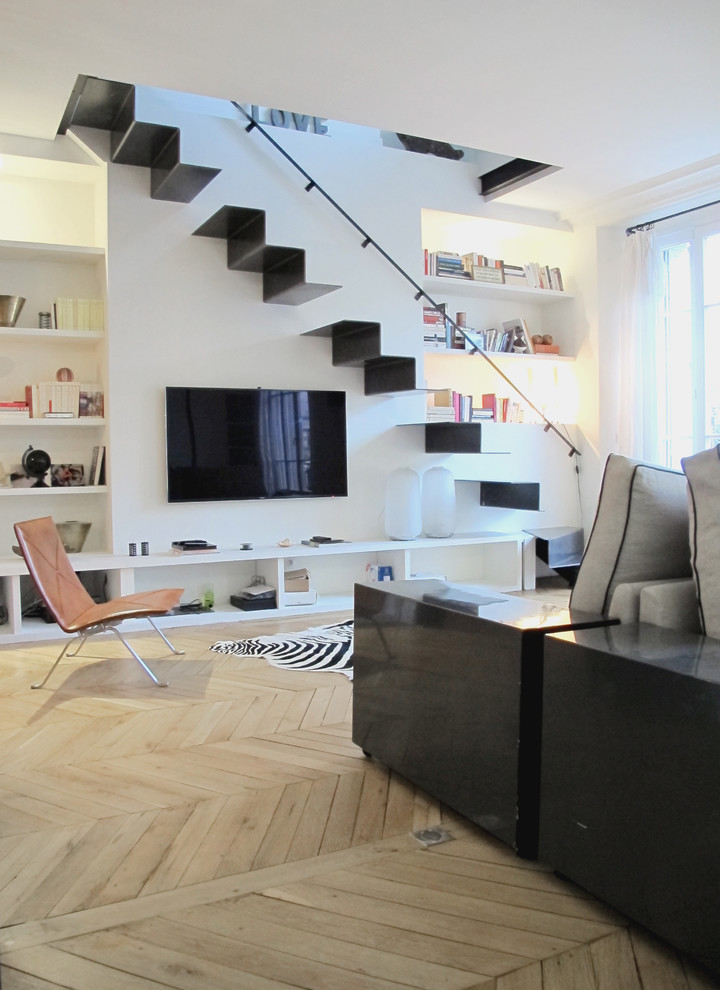 Bild på ett mellanstort funkis allrum med öppen planlösning, med vita väggar, ljust trägolv och en väggmonterad TV