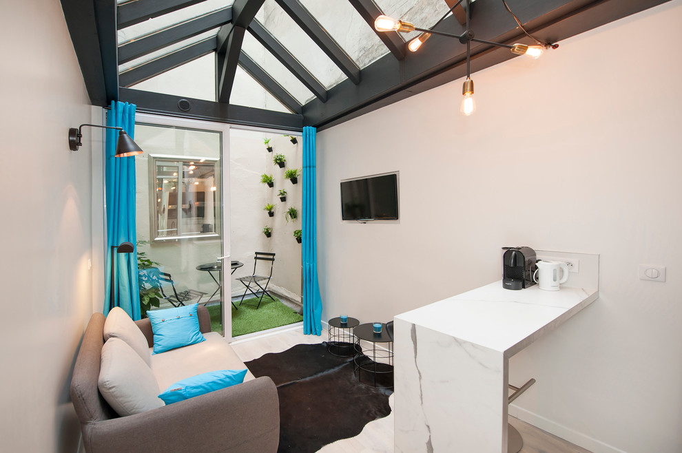 Cette photo montre une petite salle de séjour tendance ouverte avec un mur blanc, parquet clair, un téléviseur fixé au mur et aucune cheminée.