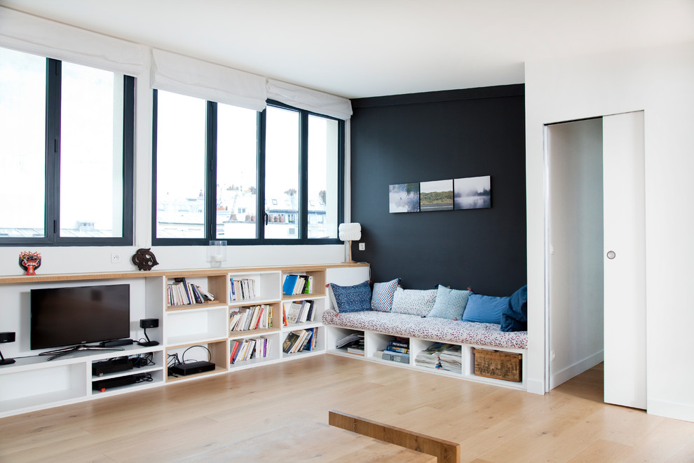Aménagement d'une grande salle de séjour scandinave ouverte avec parquet clair, une bibliothèque ou un coin lecture, un téléviseur indépendant et un mur multicolore.