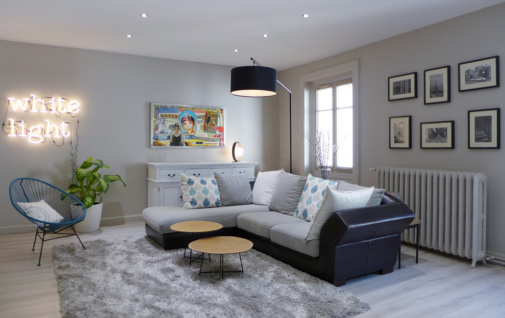 Diseño de sala de estar contemporánea grande sin chimenea con paredes grises, suelo de madera clara, televisor independiente y suelo gris