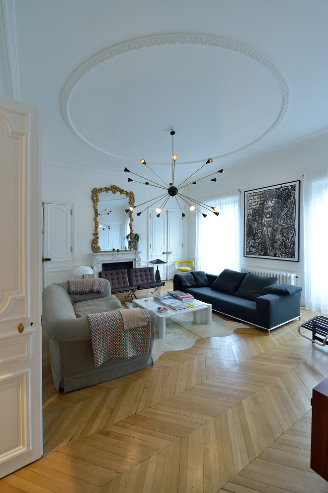 Exemple d'une salle de séjour moderne avec un mur blanc, parquet clair, une cheminée standard, un manteau de cheminée en béton et aucun téléviseur.