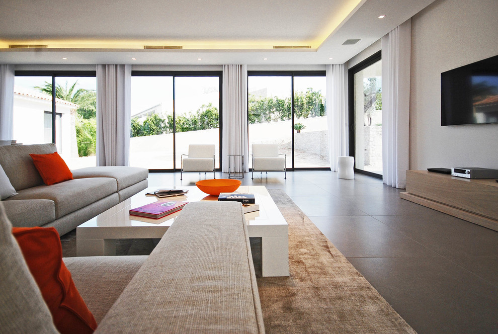 Cette image montre une salle de séjour design ouverte avec un mur blanc, un téléviseur fixé au mur et un sol gris.