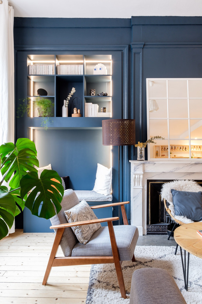 Foto de sala de estar abierta nórdica grande con paredes azules, suelo de madera clara, todas las chimeneas y marco de chimenea de piedra